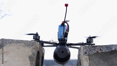 Horizontal shot of a tactical FPV kamikaze drone with a mounted explosive payload taking off from a concrete structure against a bright sky background