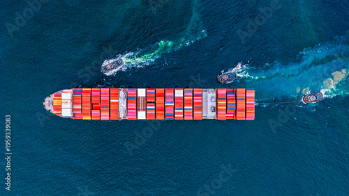 Aerial top view tugboat pushing container cargo ship going to yerminal commercial port for business logistics.