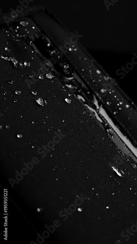 Cinematic slow motion of water splashing across a fabric surface, forming droplets that bounce and scatter. Highlights hydrophobic properties and durability
