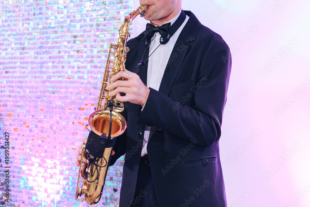 Naklejka premium young man in black smoking playing saxophone, cropped, unrecognizable