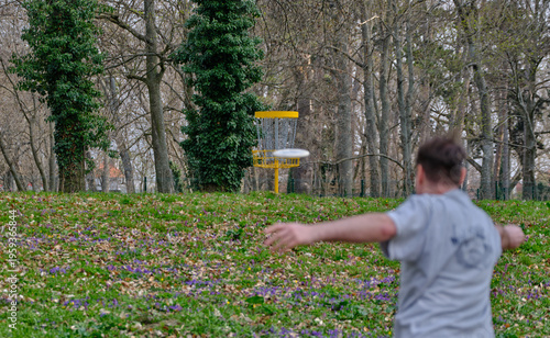 Discgolf basket with player throwing a final shot