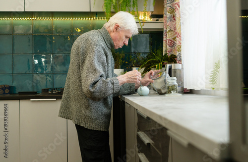 Canvas-taulu Side view of a senior citizen with hunched back preparing tea