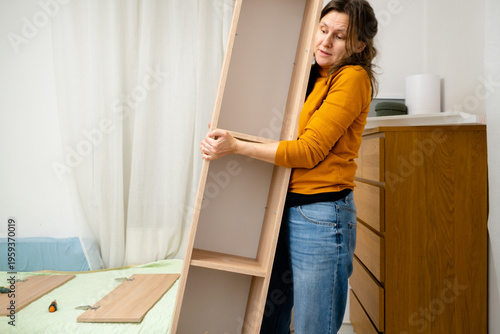 фотографія A strong woman lifts a heavy small cabinet by herself, showcasing capability in furniture handling