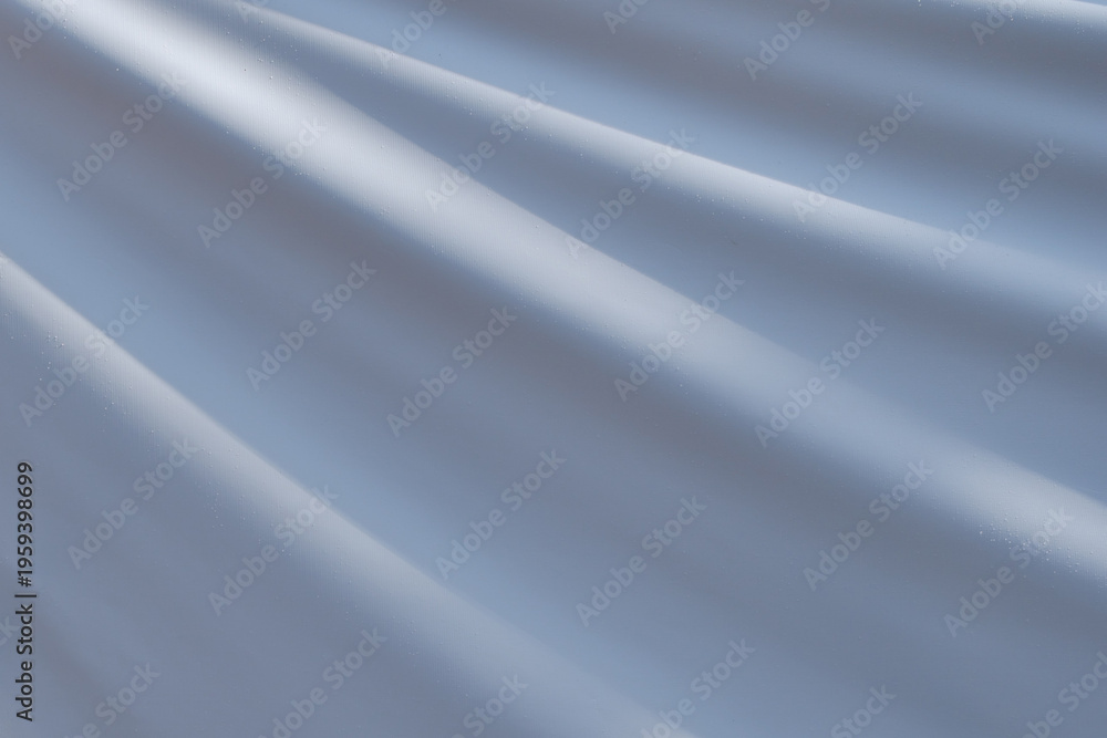 Fototapeta premium Textured, wavy surface made of waterproof gray-blue fabric covered with fine dew droplets.