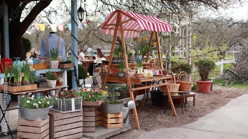 Easter exterior market stall with spring flowers, wicker baskets, bunny shaped candles, and festive decorations. Cozy outdoor garden shop with blooming plants in pots and seasonal holiday display.