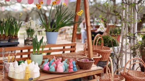 Easter exterior market stall with spring flowers, wicker baskets, bunny shaped candles, and festive decorations. Cozy outdoor garden shop with blooming plants in pots and seasonal holiday display.