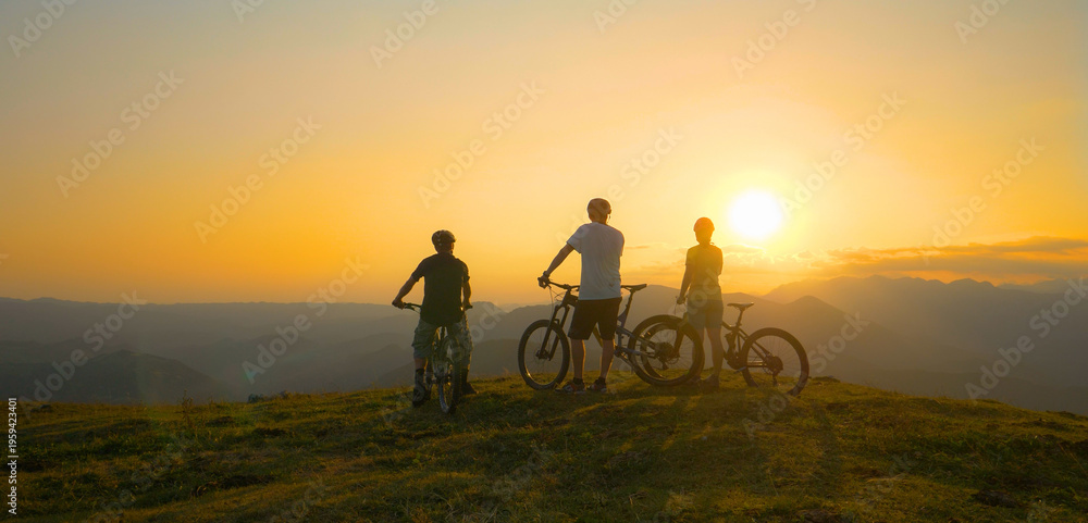 Fototapeta premium LENS FLARE: Group of fit tourists on bicycles observes the golden sunrise.
