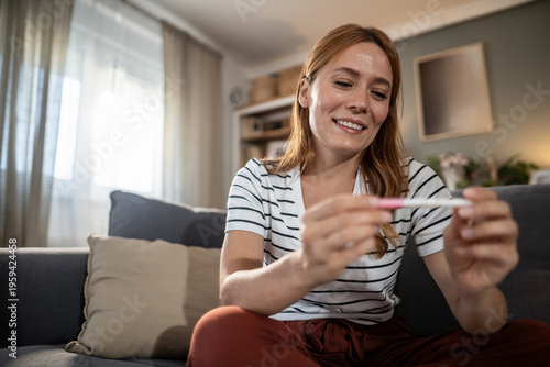 Fotografía Woman smiling holding positive pregnancy test result at home