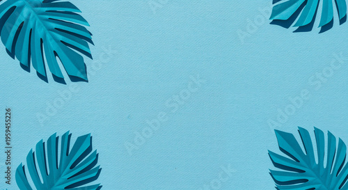 top view of blue exotic paper cut palm leaves on blue background with copy space