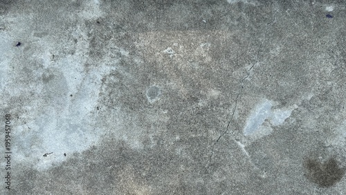 Straight-on capture of a weathered grey concrete floor showing fine hairline cracks and porous water stains.