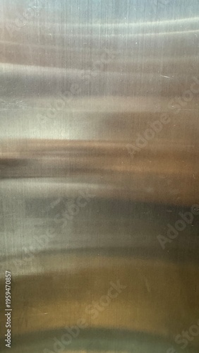 Abstract background of brushed stainless steel reflecting warm and cool tones across a horizontal grain.