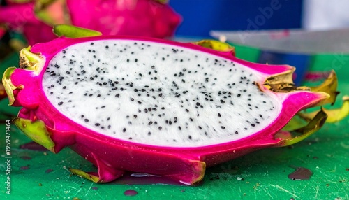 Fresh sliced white dragon fruit on a green cutting board in a traditional wet market.