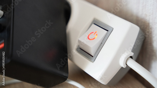 Obraz na plátne Close up of illuminated power switch with red light on white extension socket in