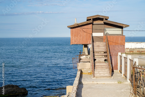 Timber pier and beach house standing over the ocean ripples under the sun. No people around