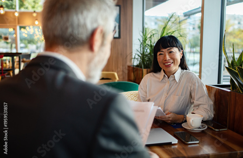 Smiling businesswoman meeting with colleague in modern cafe
