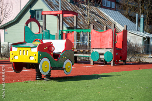 Childrens playground with colorful car spring rider and play structures in the afternoon sun