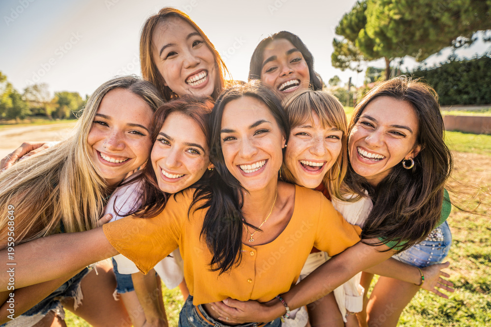 Obraz premium Multi ethnic group of young women hugging outside - Happy girlsfriends having fun laughing out loud on city street - Female community concept with cheerful girls standing together - Women power
