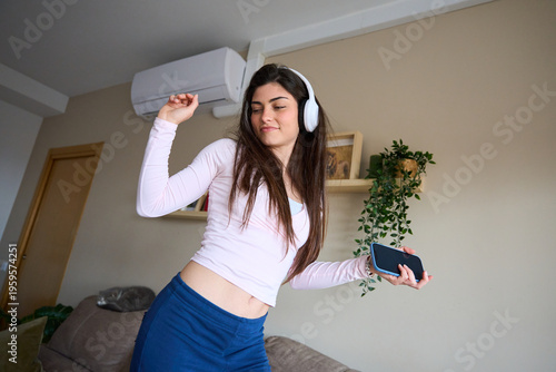 Woman dancing to music with headphones at home