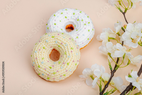 Handmade crocheted donuts with blooming cherry branches. Festive Easter, greeting card