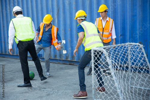 Construction workers playing football at container yard during break time