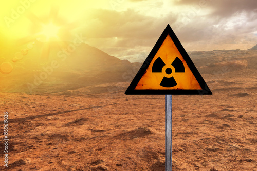 Obraz na płótnie yellow triangular radiation hazard sign stands in desolate, rocky desert landsca