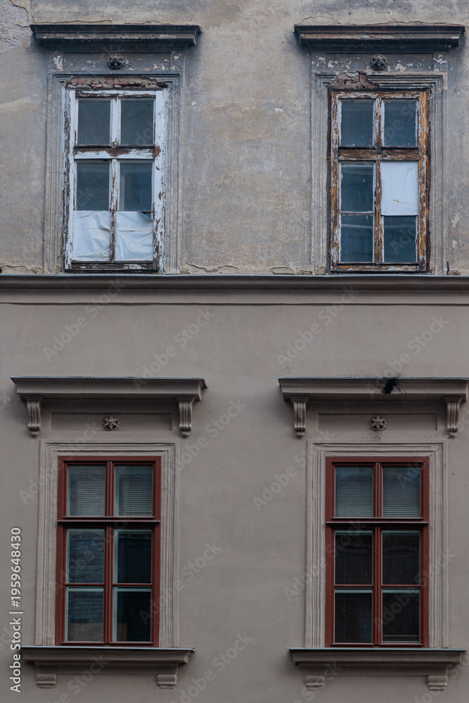 Obraz premium Old Building Facade With Weathered Windows and Rustic Architectural Details in Urban Setting