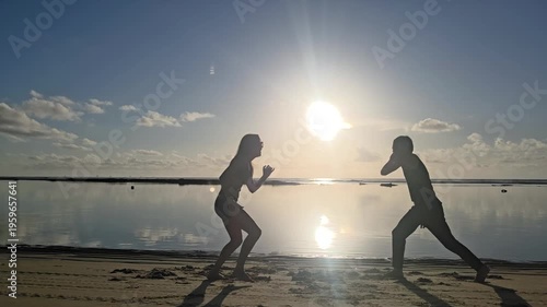 silhueta de casal jogando capoeira na praia 