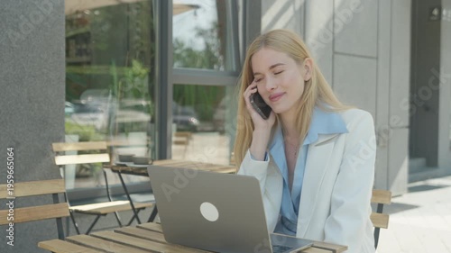 Smiling Businesswoman Talking On Smartphone While Working On Laptop Outdoors