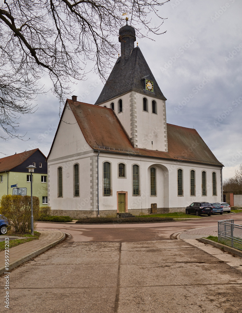 Naklejka premium Historische Dorfkirche St. Wenzel in Zöschen mit charakteristischem Turm an einer Straßenkreuzung unter bewölktem Himmel, Leuna, Saalekreis, Sachsen-Anhalt, Deutschland