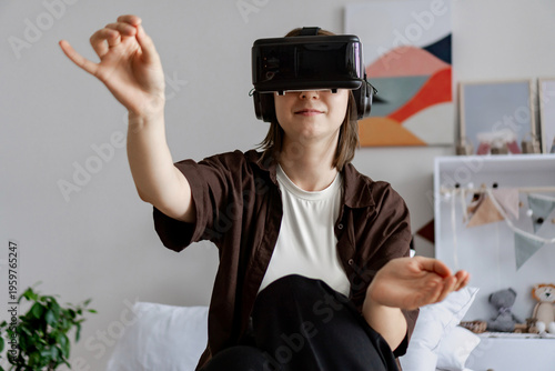 Young adult wearing VR headset at home holding virtual palette and paint brush. Young woman painting in virtual reality app. Concepts of gaming, immersive technology, home entertainment.