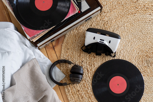 Flat lay photo of vinyl records accompanied by headphones, vintage record player and virtual reality headset. Concepts of blending classic and modern elements, nostalgia and technological evolution.