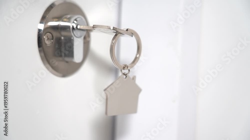 Key door house. A key in the door with a keychain in the shape of a house close-up. The concept of acquiring your own home. High quality FullHD footage