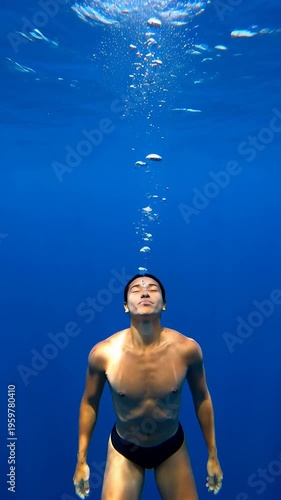Man exhaling bubbles underwater in clear blue sea