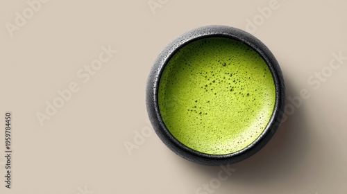 Elegant green matcha tea in a textured black bowl on beige surface