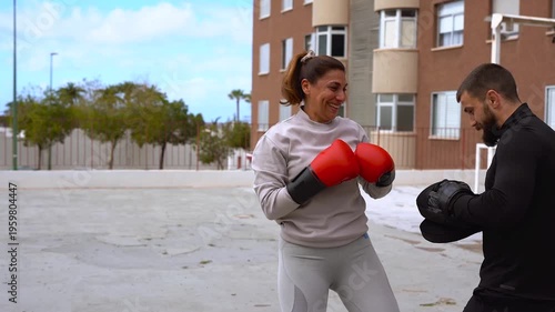 Personal trainer doing boxing sport exercise routine with mature latin woman in the city - Workout, fitness coach and healthy lifestyle concept