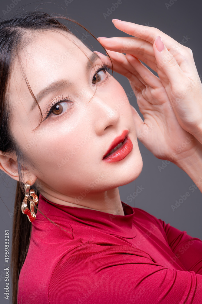 Obraz premium Elegant Asian woman in red fashion outfit posing in studio, showcasing beauty, confidence and modern style, flawless skin with bold makeup, luxury portrait highlighting feminine strength and glamour.