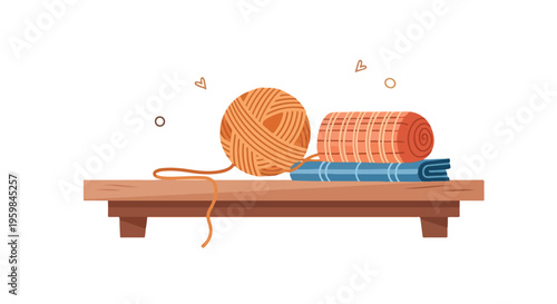 Flat lay of a ball of yarn, a rolled-up orange blanket, and folded blue towels on a wooden bench against a white background.