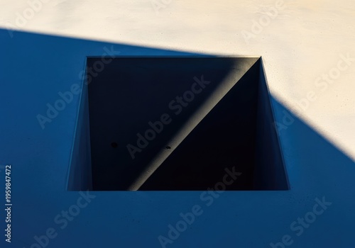 Sunlight creates a stark geometric shadow on a smooth, empty surface, defining a central blank void for abstract concepts, background, illumination, dramatic