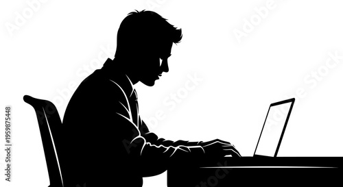 Silhouette of a young man working on a laptop computer at a desk in a dimly lit room