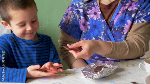 Smiling Child Receiving Chocolate Treat from Adult at Table, Happy Family Bonding and Shared Joy, Candid Indoor Lifestyle Moment