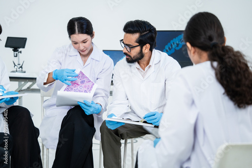 фотографія Group of diverse medical scientists in lab coats discussing pathology biopsy results on printed reports in a clinical lab setting