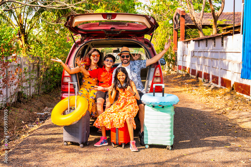 Young Indian parents and kids cheering in a car trunk for a family vacation