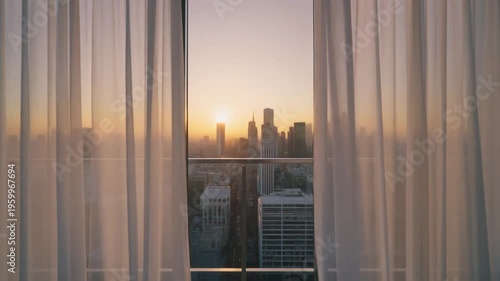 A serene cityscape at sunset viewed through a window with sheer curtains in a modern building