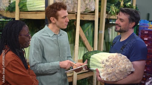 Warehouse workers checking vegetable inventory with a digital tablet