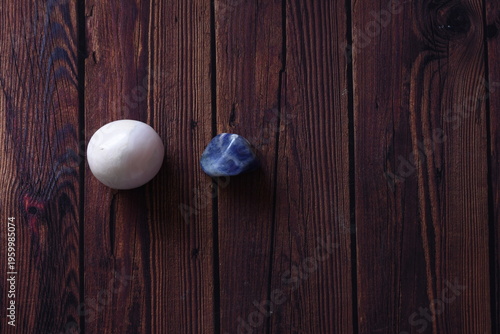 Quadro em tela Lapis lazuli and rhodonite crystals placed on a rustic wooden table, showcasing deep blue and pink natural tones with organic texture