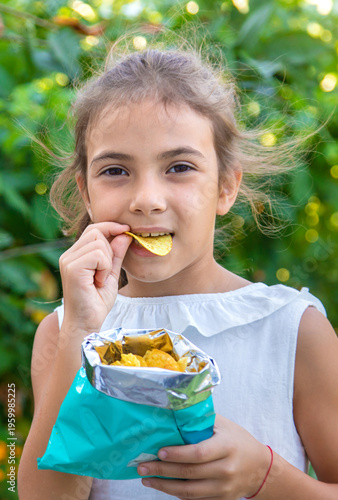 The child is eating chips. Selective focus.