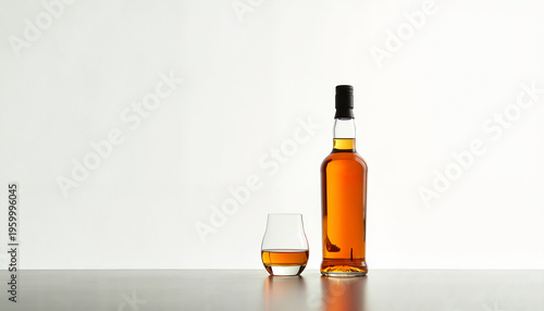 Whiskey bottle and glass on wooden table against white background
