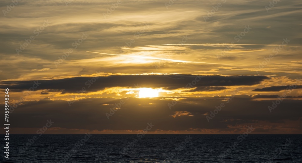 Obraz premium Expansive seaside sky at sunset with sun shining through layered clouds nature scene