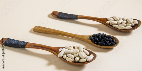 Diferentes tipos de alubias sobre cucharas de madera sobre fondo blanco