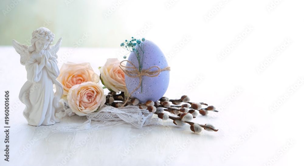Fototapeta premium Easter holiday background. Beautiful angel figurine with easter egg, pussy willow and rose flowers on light table close up. symbol of Easter, Christianity religion, faith in God, prayer. soft focus